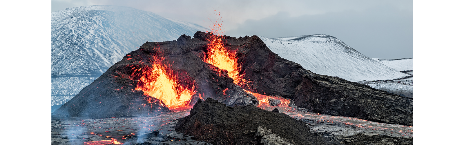 An erupting volcano surrounded by snowy peaks. 